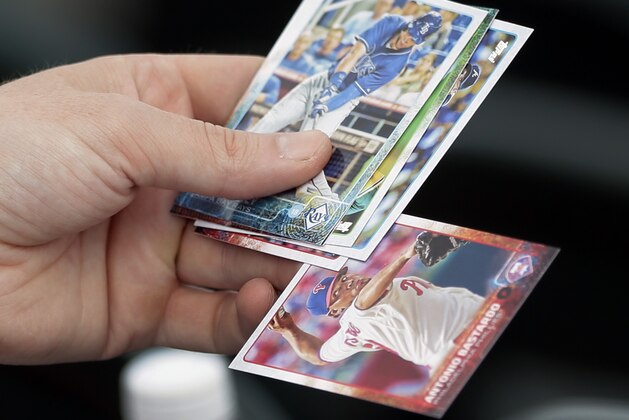 A baseball fan looks through his card collection for an Antonio Bastardo card during batting practice of a spring training exhibition baseball game against the Baltimore Orioles in Bradenton, Fla., Tuesday, March 24, 2015. (AP Photo/Carlos Osorio)
