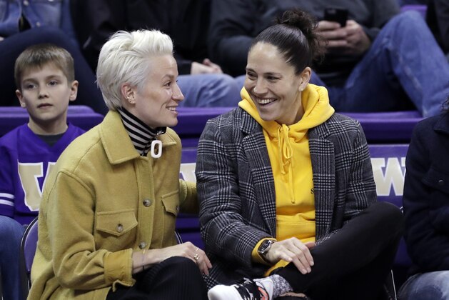 Seattle Reign FC's Megan Rapinoe, left, and Seattle Storm's Sue Bird look on during an NCAA college basketball game between Washington and Oregon Sunday, Jan. 27, 2019, in Seattle. (AP Photo/Elaine Thompson)