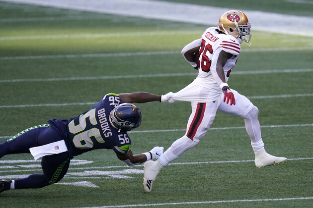 Seattle Seahawks linebacker Jordyn Brooks (56) grabs the jersey of San Francisco 49ers running back Tevin Coleman, right, during the first half of an NFL football game, Sunday, Nov. 1, 2020, in Seattle. (AP Photo/Elaine Thompson)