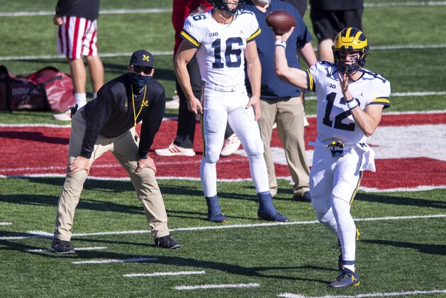 Michigan head coach Jim Harbaugh, left, watches as quarterback Cade McNamara (12) warms up before an NCAA college football game against Indiana, Saturday, Nov. 7, 2020, in Bloomington, Ind. (AP Photo/Doug McSchooler)