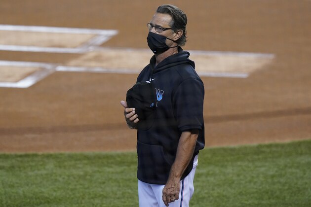 Wearing a mask to help prevent the spread of COVID-19, Miami Marlins manager Don Mattingly stands for the singing of the National Anthem before the start of a baseball game against the Tampa Bay Rays, Sunday, Aug. 30, 2020, in Miami. (AP Photo/Wilfredo Lee)