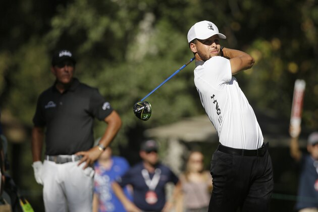Stephen Curry hits from the 18th tee of the Silverado Resort North Course as Phil Mickelson looks on during the pro-am event of the Safeway Open PGA golf tournament Wednesday, Sept. 25, 2019, in Napa, Calif. (AP Photo/Eric Risberg)