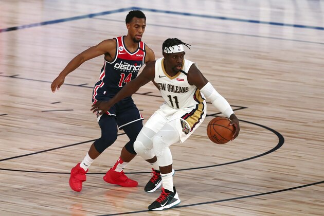 New Orleans Pelicans guard Jrue Holiday (11) handles the ball against Washington Wizards guard Ish Smith (14) during the fourth quarter of an NBA basketball game Friday, Aug. 7, 2020, in Lake Buena Vista, Fla. (Kim Klement/Pool Photo via AP)