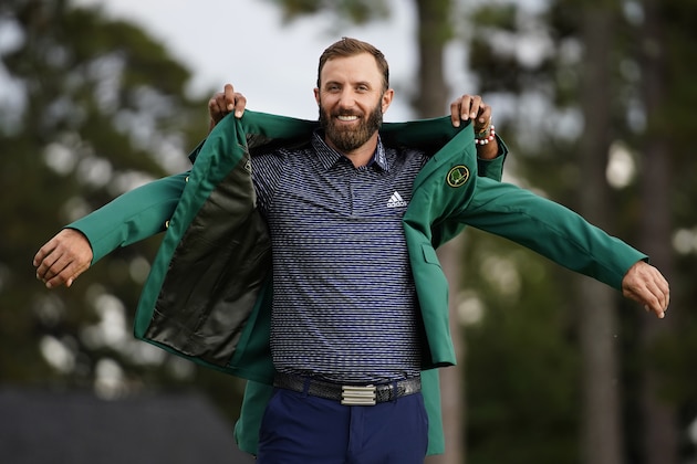 Tiger Woods helps Masters champion Dustin Johnson with his green jacket after his victory at the Masters golf tournament Sunday, Nov. 15, 2020, in Augusta, Ga. (AP Photo/Matt Slocum)