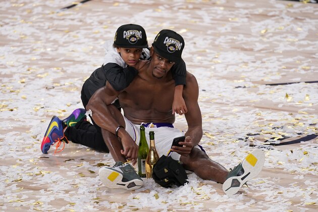 Los Angeles Lakers' Rajon Rondo sits in the confetti with his son Rajon Jr. after the Lakers defeated the Miami Heat 106-93 in Game 6 of basketball's NBA Finals, Sunday, Oct. 11, 2020, in Lake Buena Vista, Fla. (AP Photo/Mark J. Terrill)