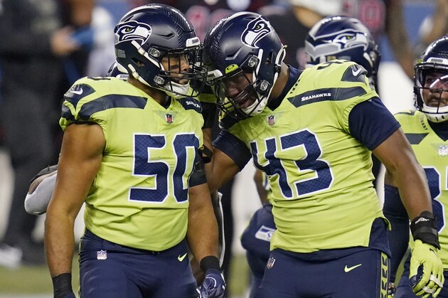 Seattle Seahawks outside linebacker K.J. Wright (50) and defensive end Carlos Dunlap (43) celebrate after a play against the Arizona Cardinals during the first half of an NFL football game, Thursday, Nov. 19, 2020, in Seattle. (AP Photo/Elaine Thompson)