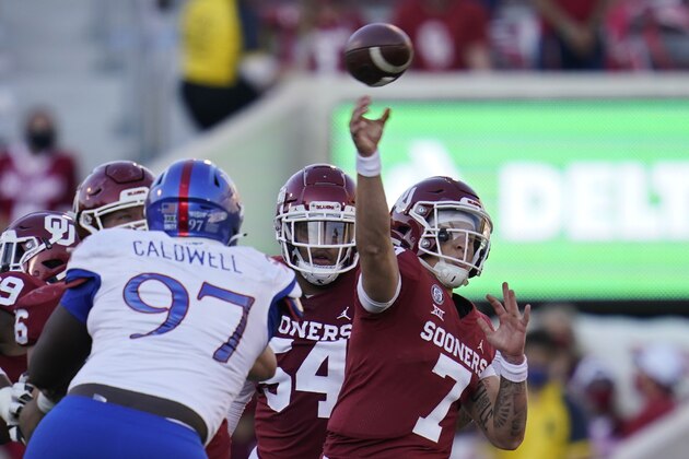 Oklahoma quarterback Spencer Rattler (7) throws under pressure from Kansas defensive lineman Kenean Caldwell (97) in the first half of an NCAA college football game in Norman, Okla., Saturday, Nov. 7, 2020. (AP Photo/Sue Ogrocki)