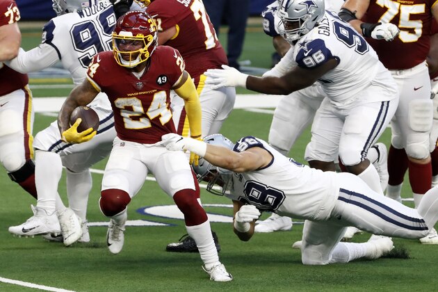 Washington Football Team running back Antonio Gibson (24) attempts to escape the grasp of Dallas Cowboys defensive end Tyrone Crawford (98) as he carries the ball in the first half of an NFL football game in Arlington, Texas, Thursday, Nov. 26, 2020. (AP Photo/Roger Steinman)