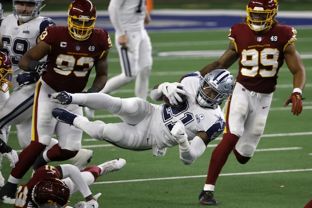 Dallas Cowboys running back Ezekiel Elliott (21) leaps forward on a carry for a first down between Washington Football Team's Cole Holcomb (55), Kamren Curl (31), Jonathan Allen (93) and Chase Young (99) in the second half of an NFL football game in Arlington, Texas, Thursday, Nov. 26, 2020. (AP Photo/Ron Jenkins)