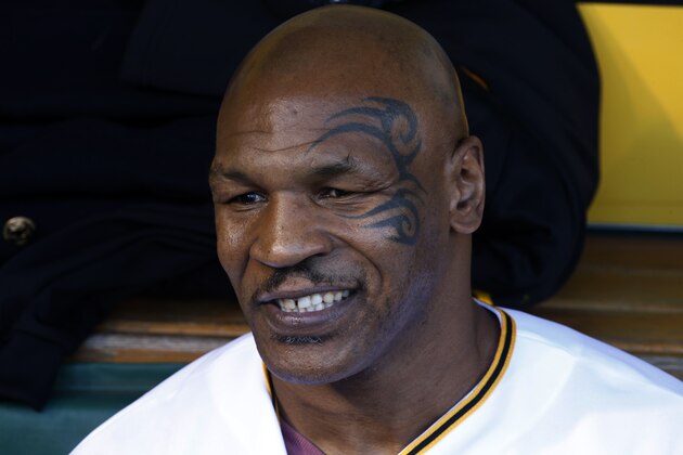 Former boxing heavyweight champion Mike Tyson sits in the Pittsburgh Pirates dugout as he waits to throw out the first pitch before  a baseball game between the Pittsburgh Pirates and the Milwaukee Brewers in Pittsburgh Thursday, April 17, 2014. (AP Photo/Gene J. Puskar)