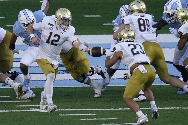 Notre Dame quarterback Ian Book (12) hands off to running back Kyren Williams (23) during the first half of an NCAA college football game against North Carolina in Chapel Hill, N.C., Friday, Nov. 27, 2020. Book scored a touchdown on the play. (AP Photo/Gerry Broome)