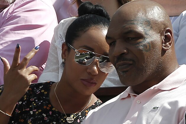 Former world heavyweight boxing champion Mike Tyson listens to a woman as Romania's Simona Halep plays Spain's Garbine Muguruza during their semifinal match of the French Open tennis tournament at the Roland Garros stadium, Thursday, June 7, 2018 in Paris. (AP Photo/Michel Euler)