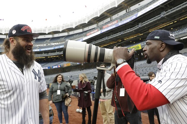 Pro-wrestler Braun Strowman, left, talks to fellow pro-wrestler Titus O'Neil, who tests out a photographer's lens on the field during warmups before a baseball game between the New York Yankees and the Detroit Tigers, Tuesday, April 2, 2019, in New York. The pair are appearing in Wrestlemania this weekend at MetLife Stadium in East Rutherford, N.J. (AP Photo/Kathy Willens)