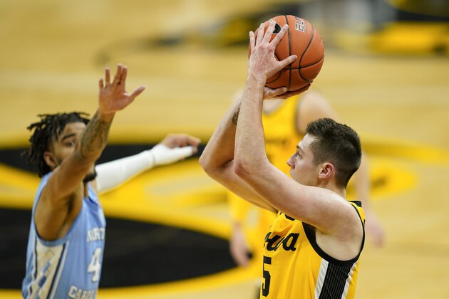 Iowa guard CJ Fredrick, right, shoots a 3-point basket ahead of North Carolina guard R.J. Davis, left, during the first half of an NCAA college basketball game, Tuesday, Dec. 8, 2020, in Iowa City, Iowa. (AP Photo/Charlie Neibergall)