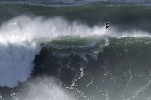A surfer vaults over a wave during a tow surfing session at Praia do Norte or North Beach in Nazare, Portugal, Thursday, Oct. 29, 2020. A big swell, generated earlier in the week by Hurricane Epsilon in the North Atlantic, reached the Portuguese west coast drawing big wave surfers to Nazare. (AP Photo/Pedro Rocha)