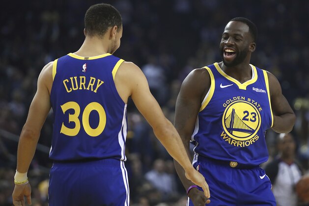 Golden State Warriors' Draymond Green, right, greets Stephen Curry (30) prior to the first half of an NBA basketball game against the Minnesota Timberwolves Monday, Dec. 10, 2018, in Oakland, Calif. The first game both have retuned to play at home since recovering from injuries. (AP Photo/Ben Margot)