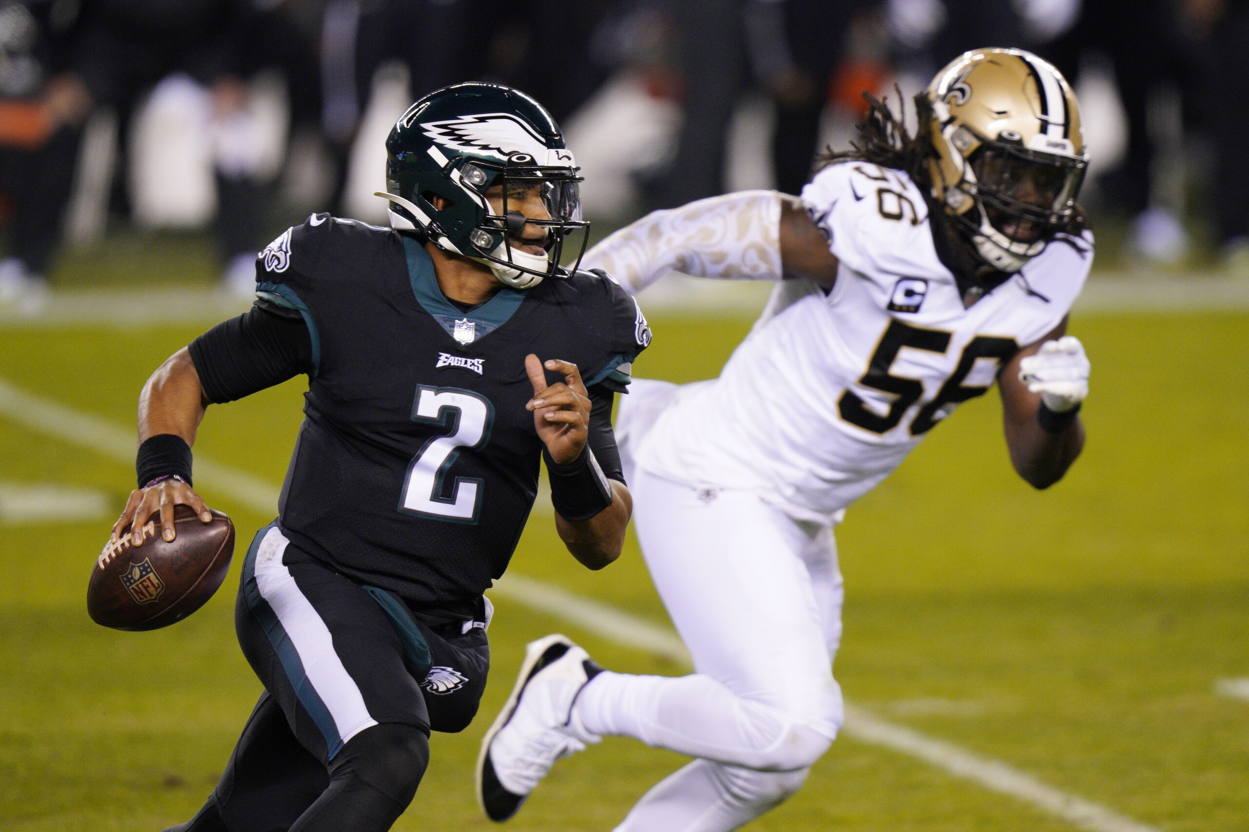 El quarterback novato Jalen Hurts, izquierda, de los Eagles de Filadelfia, trata de huir de Demario Davis, de los Saints de Nueva Orleans, durante el duelo de NFL del domingo 13 de diciembre de 2020, en Filadelfia. (AP Foto/Chris Szagola)