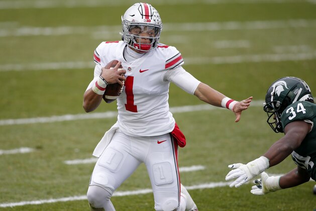 Ohio State quarterback Justin Fields, left, rushes against Michigan State's Antjuan Simmons during the first half of an NCAA college football game, Saturday, Dec. 5, 2020, in East Lansing, Mich.   (AP Photo/Al Goldis)