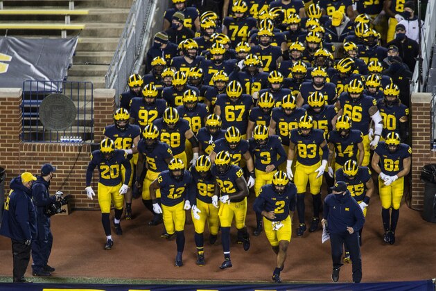 Michigan head coach Jim Harbaugh, bottom right, leads his team out of the Michigan Stadium tunnel before an NCAA college football game against Wisconsin in Ann Arbor, Mich., Saturday, Nov. 14, 2020. (AP Photo/Tony Ding)