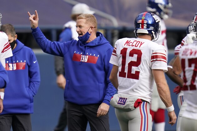 New York Giants offensive coordinator Jason Garrett gestures as he stands next to quarterback Colt McCoy (12) before an NFL football game against the Seattle Seahawks, Sunday, Dec. 6, 2020, in Seattle. Garrett's gesture is the hand sign for the University of Texas, where McCoy was the starting quarterback from 2006 to 2009. (AP Photo/Elaine Thompson)