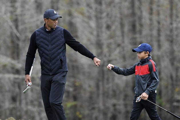 Tiger Woods, left, gives his son Charlie a fist bump after Charlie made a putt on the 12th green during a practice round of the Father Son Challenge golf tournament, Thursday, Dec. 17, 2020, in Orlando, Fla. (AP Photo/Phelan M. Ebenhack)