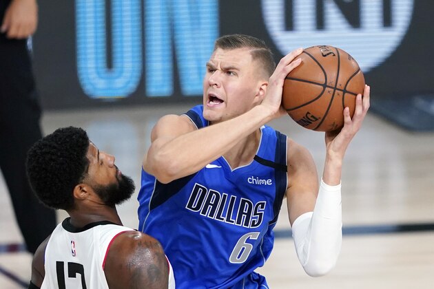 FILE - Dallas Mavericks' Kristaps Porzingis (6) is defended by Los Angeles Clippers' Paul George (13) during the first half of an NBA basketball first round playoff game in Lake Buena Vista, Fla., in this Friday, Aug. 21, 2020, file photo. Porzingis will miss the start of the season recovering from surgery for a knee he injured in his first career playoff game for Dallas. The Mavericks say the 7-foot-3 Latvian's return is on schedule, likely in January. (AP Photo/Ashley Landis, Pool, File)
