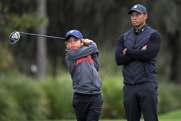 Tiger Woods, right, watches as his son Charlie tees off on the 12th hole during a practice round of the Father Son Challenge golf tournament, Thursday, Dec. 17, 2020, in Orlando, Fla. (AP Photo/Phelan M. Ebenhack)