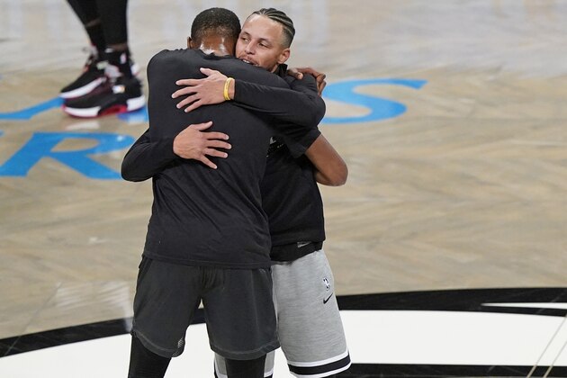 Golden State Warriors guard Stephen Curry, right, embraces Brooklyn Nets forward Kevin Durant during pregame warmups before the start of an opening night NBA basketball game between the Warriors and the Nets, Tuesday, Dec. 22, 2020, in New York. (AP Photo/Kathy Willens)