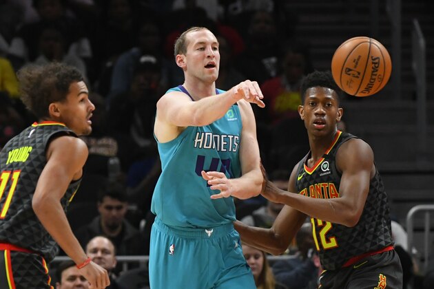 Charlotte Hornets center Cody Zeller passes as Atlanta Hawks guard Trae Young, left, and Atlanta Hawks forward De'Andre Hunter, right, defend during an NBA basketball game Monday, March 9, 2020, in Atlanta. (AP Photo/John Amis)