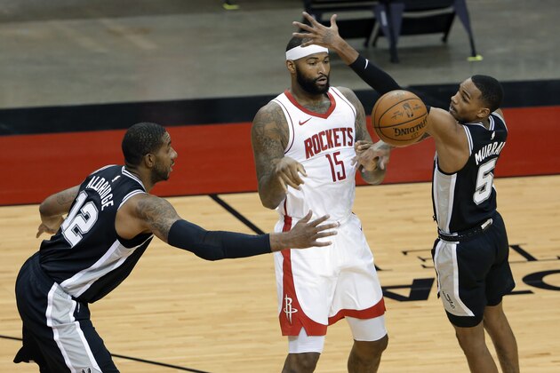 Houston Rockets center DeMarcus Cousins (15) passes the ball between San Antonio Spurs forward LaMarcus Aldridge (12) and guard Dejounte Murray (5) during the first half of an NBA basketball game Tuesday, Dec. 15, 2020, in Houston. (AP Photo/Michael Wyke)