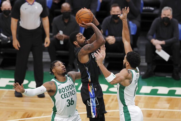 Brooklyn Nets' Kyrie Irving shoots against Boston Celtics' Marcus Smart (36) and Jayson Tatum (0) during the first half of an NBA basketball game, Friday, Dec. 25, 2020, in Boston. (AP Photo/Michael Dwyer)