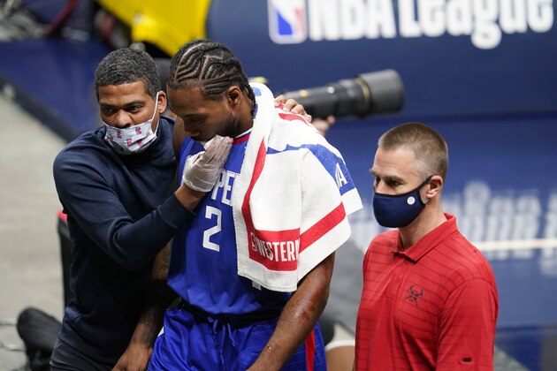Los Angeles Clippers forward Kawhi Leonard, center, is accompanied off the court during the second half of the team's NBA basketball game against the Denver Nuggets on Friday, Dec. 25, 2020, in Denver. (AP Photo/David Zalubowski)