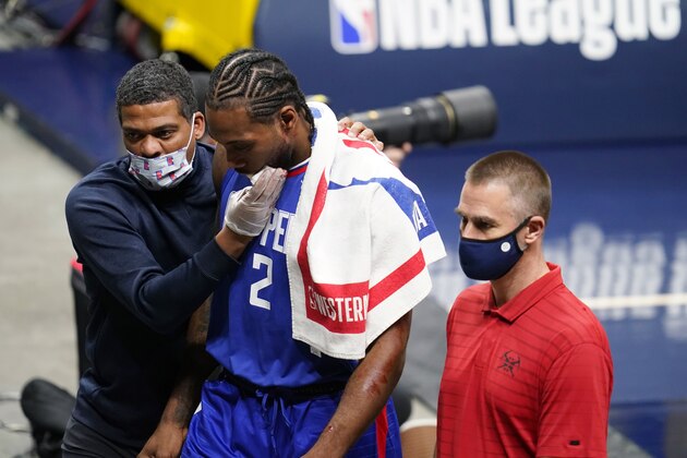 Los Angeles Clippers forward Kawhi Leonard, center, is accompanied off the court during the second half of the team's NBA basketball game against the Denver Nuggets on Friday, Dec. 25, 2020, in Denver. (AP Photo/David Zalubowski)