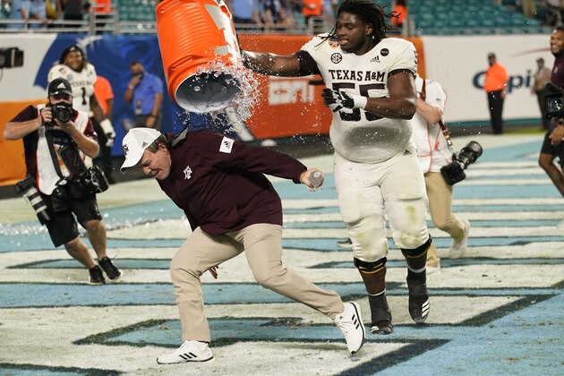 Texas A&M offensive lineman Kenyon Green (55) douses head coach Jimbo Fisher at the end of the Orange Bowl NCAA college football game, Saturday, Jan. 2, 2021, in Miami Gardens, Fla. Texas A&M defeated North Carolina 41-27. (AP Photo/Lynne Sladky)