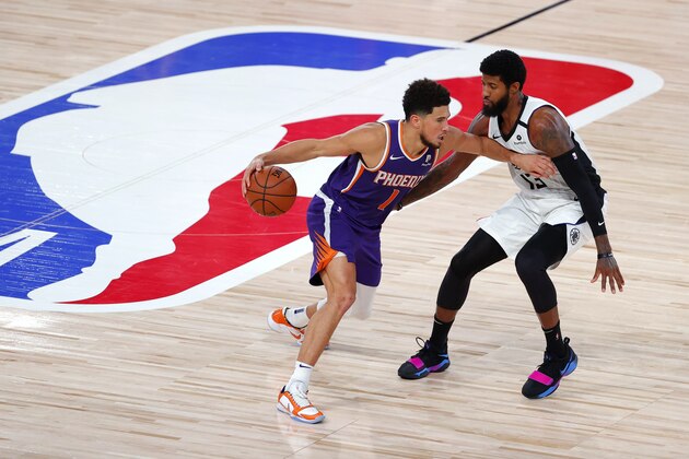 Los Angeles Clippers' Paul George defends against Phoenix Suns' Devin Booker (1) during an NBA basketball game Tuesday, Aug. 4, 2020, in Lake Buena Vista, Fla. (Kevin C. Cox/Pool Photo via AP)