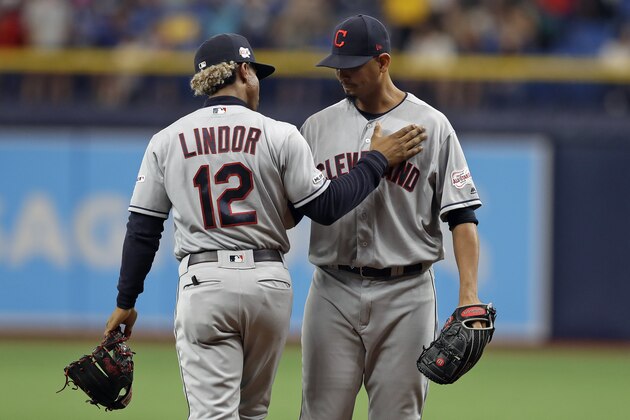 Cleveland Indians shortstop Francisco Lindor (12) pats Indians pitcher Carlos Carrasco on the chest after he warmed up during the seventh inning of a baseball game against the Tampa Bay Rays Sunday, Sept. 1, 2019, in St. Petersburg, Fla. Carrasco is making his first appearance since May, when he was diagnosed with leukemia. (AP Photo/Chris O'Meara)