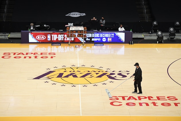 A Staples Center staff member with a mask on cleans the floor before an NBA preseason basketball game between the Los Angeles Clippers and the Los Angeles Lakers in Los Angeles, Sunday, Dec. 13, 2020. NBA hopes to kick off the regular season on Dec. 22, under pandemic. (AP Photo/Kyusung Gong)