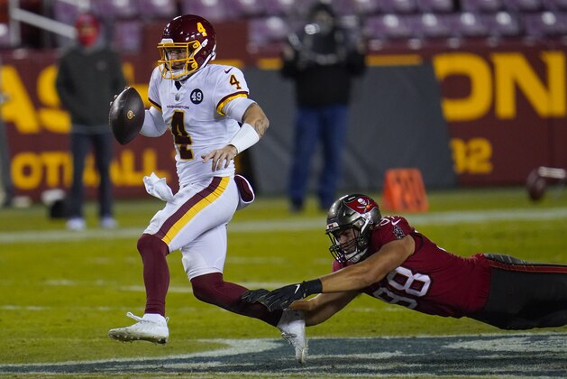 Washington Football Team quarterback Taylor Heinicke (4) his chased down by Tampa Bay Buccaneers outside linebacker Anthony Nelson (98) during the second half of an NFL wild-card playoff football game, Saturday, Jan. 9, 2021, in Landover, Md. (AP Photo/Julio Cortez)