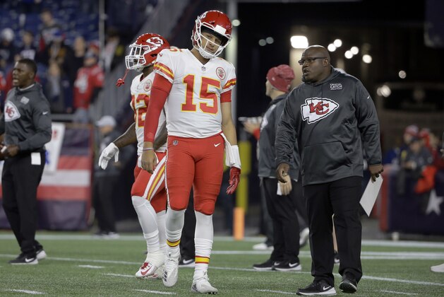 Kansas City Chiefs quarterback Patrick Mahomes listens to offensive coordinator Eric Bieniemy, right, as he warms up before an NFL football game against the New England Patriots, Sunday, Oct. 14, 2018, in Foxborough, Mass. (AP Photo/Steven Senne)