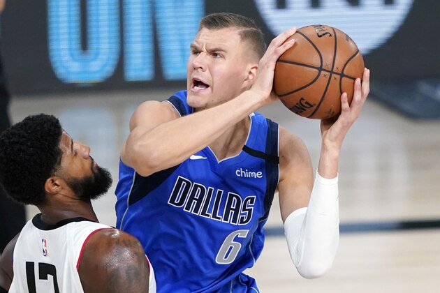 FILE - Dallas Mavericks' Kristaps Porzingis (6) is defended by Los Angeles Clippers' Paul George (13) during the first half of an NBA basketball first round playoff game in Lake Buena Vista, Fla., in this Friday, Aug. 21, 2020, file photo. Porzingis will miss the start of the season recovering from surgery for a knee he injured in his first career playoff game for Dallas. The Mavericks say the 7-foot-3 Latvian's return is on schedule, likely in January. (AP Photo/Ashley Landis, Pool, File)
