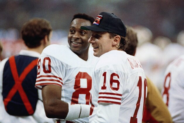 San Francisco 49ers quarterback Joe Montana (16) chats with wide receiver Jerry Rice late in Sunday, Jan. 29, 1990 Super Bowl thrashing of the Denver Broncos, 55-10. Rice caught three of Montana's five touchdown passes in the game at New Orleans. (AP Photo/Lennox McLendon)