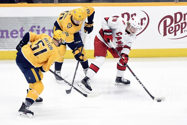 Carolina Hurricanes center Ryan Dzingel (18) is defended by Nashville Predators center Colton Sissons (10) and left wing Austin Watson (51) during the third period of an NHL hockey game Tuesday, Feb. 18, 2020, in Nashville, Tenn. The Hurricanes won 4-1. (AP Photo/Mark Zaleski)