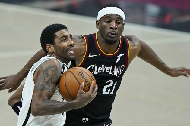 Brooklyn Nets' Kyrie Irving, front, drives to the basket against Cleveland Cavaliers' Damyean Dotson during the second half of an NBA basketball game, Wednesday, Jan. 20, 2021, in Cleveland. The Cavaliers won 147-135 in double-overtime. (AP Photo/Tony Dejak)
