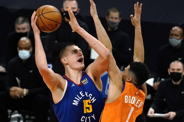 Denver Nuggets center Nikola Jokic shoots over Phoenix Suns guard Devin Booker (1) during the first half of an NBA basketball game Friday, Jan. 22, 2021, in Phoenix. (AP Photo/Rick Scuteri)