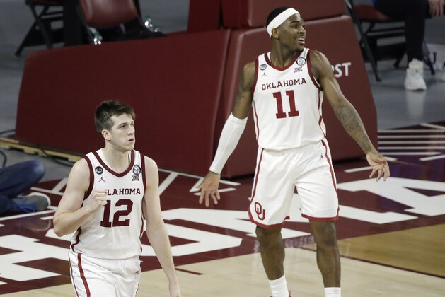 Oklahoma guards Austin Reaves (12) and De'Vion Harmon (11) react after beating Kansas in an NCAA college basketball game in Norman, Okla., Saturday, Jan. 23, 2021. (AP Photo/Garett Fisbeck)