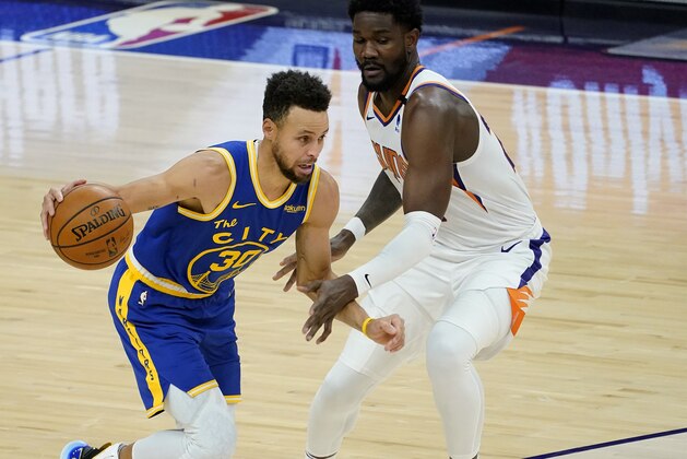 Golden State Warriors guard Stephen Curry (30) drives as Phoenix Suns center Deandre Ayton defends during the first half of an NBA basketball game Thursday, Jan. 28, 2021, in Phoenix. (AP Photo/Matt York)
