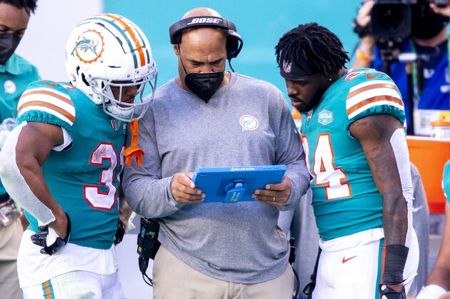 From left, Miami Dolphins running back DeAndre Washington (31), Miami Dolphins running backs coach Eric Studesville and Miami Dolphins running back De'Lance Turner (34) review a play on a Microsoft Surface tablet as Miami Dolphins quarterback Tua Tagovailoa (1) sits on the bench on the sidelines as the Dolphins take on the Kansas City Chiefs during an NFL football game, Sunday, Dec. 13, 2020, in Miami Gardens, Fla. (AP Photo/Doug Murray)