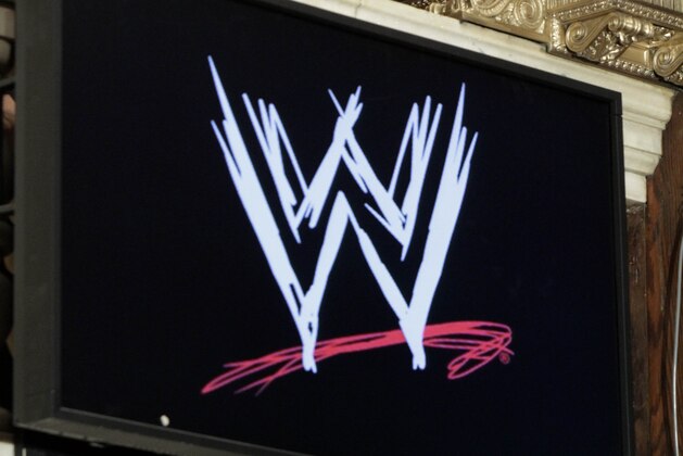 WWE wrestlers Triple H, left, and Kelly Kelly pose photos at a phone post on the floor of the New York Stock Exchange after they rang the opening bell, Wednesday, Oct. 27, 2010, marking 10 years of trading for World Wrestling Entertainment at the NYSE. (AP Photo/Richard Drew)