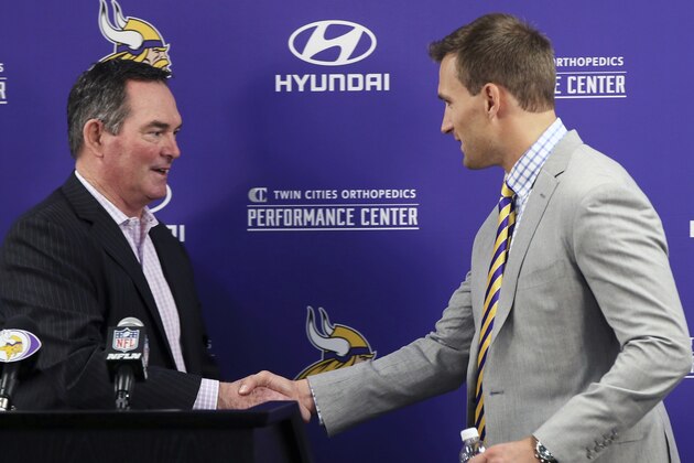 Minnesota Vikings new quarterback Kirk Cousins, right, is welcomed to the podium by head coach Mike Zimmer before addressing the media at a news conference after he was introduced after signing a three-year, $84 million contract at the NFL football team's new headquarters Thursday, March 15, 2018, in Eagan, Minn. (AP Photo/Jim Mone)
