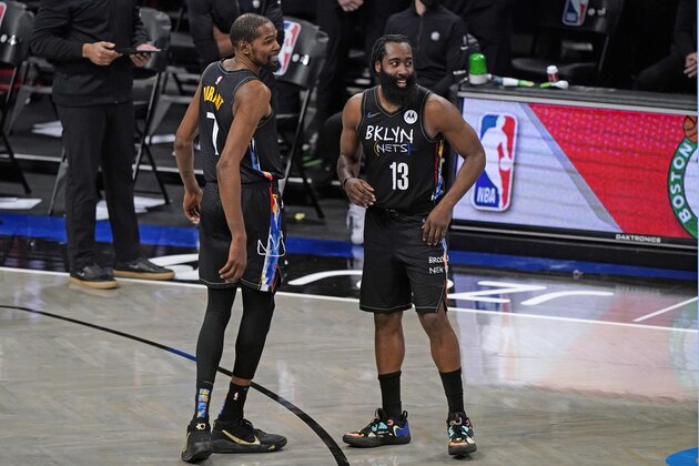 Brooklyn Nets forward Kevin Durant (7) and Nets guard James Harden (13) look toward teammate Kyrie Irving who hit his free throws during the fourth quarter of an NBA basketball game against the Los Angeles Clippers, Tuesday, Feb. 2, 2021, in New York. The Nets defeated the Clippers 124-120. (AP Photo/Kathy Willens)